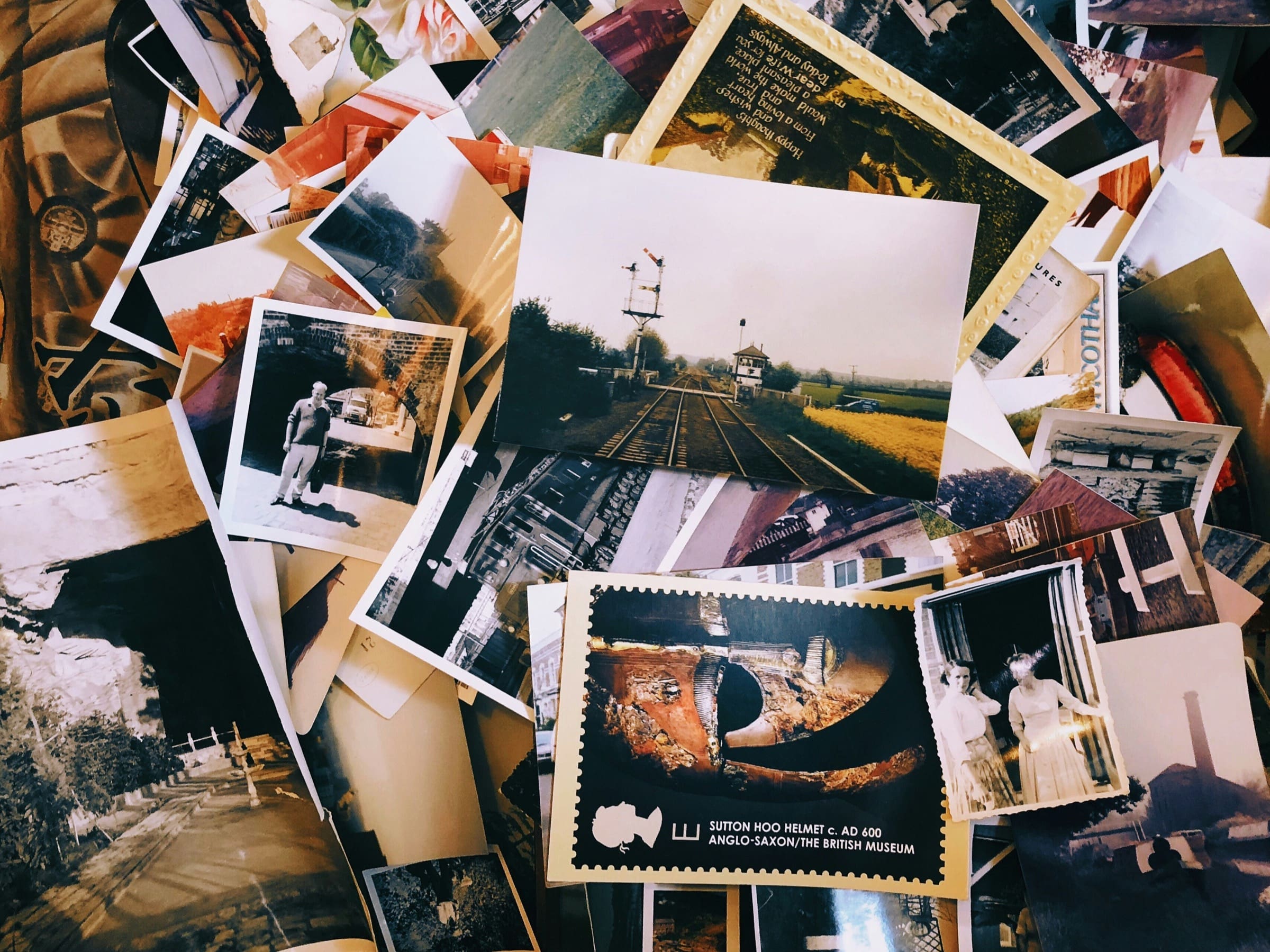 A loose pile of old printed photographs and postcards